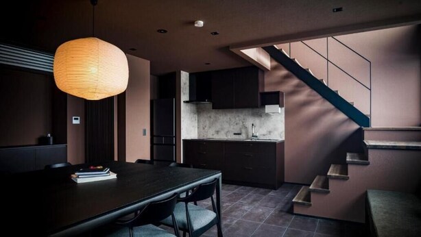 A modern kitchen with dark cabinetry, a marble countertop, and a staircase leading to an upper level. - monel (Nakafurano)