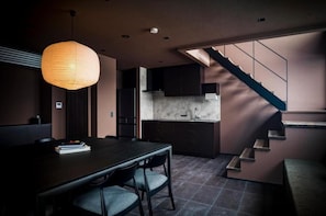 Una cocina moderna con armarios oscuros, encimera de mármol y una escalera que sube a un nivel superior.