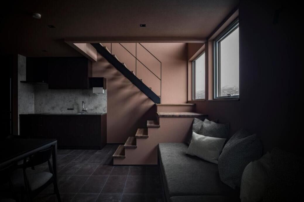 Un interior moderno con una escalera, un sofá y una zona de cocina.
