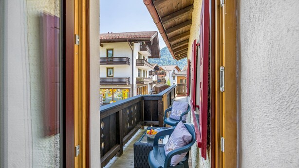 Un balcon offrant une vue sur des bâtiments traditionnels et des montagnes.