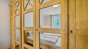 Une pièce en bois avec un lit, une fenêtre avec des rideaux et un luminaire.