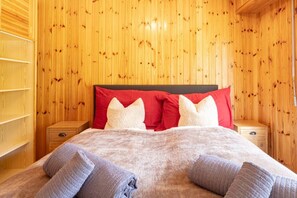 A wooden-paneled room with a bed, red and white pillows, and a blanket. - Panoramic view, 2 bedrooms, covered parking (Nendaz)