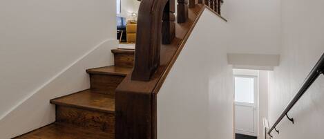A wooden staircase with a handrail, leading to an upper floor.