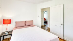 Ein Schlafzimmer mit einem Bett, einem Nachttisch mit Lampe, einer Tür und einem Deckenventilator.