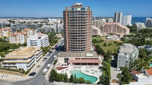 A high-rise hotel with multiple balconies, a swimming pool, and a view of the cityscape. - #357 Sea View Getaway in Portimão | Pool & Spacious (Portimão)