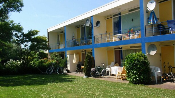 Um edifício de dois andares com varandas, área de estar ao ar livre e bicicletas.