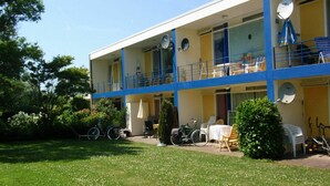 Um edifício de dois andares com varandas, área de estar externa e bicicletas.