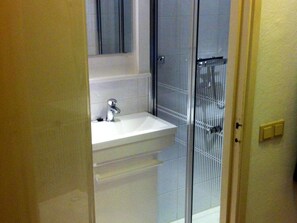 Een badkamer met een wit wastafelmeubel, een spiegel erboven en een douchecabine van glas.