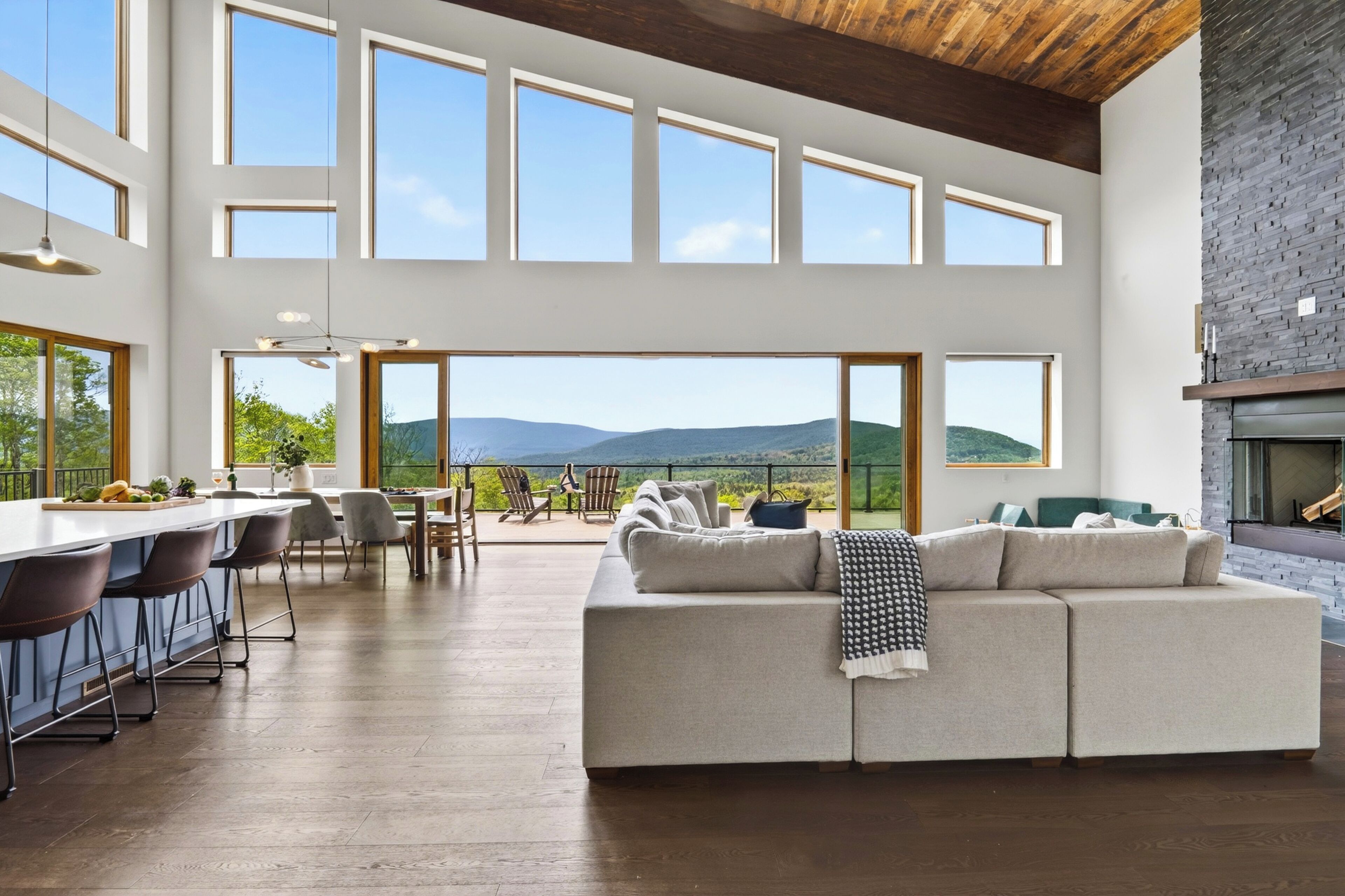 A spacious living area with a large sofa, dining table, and chairs, a kitchen area with bar stools, and a fireplace.