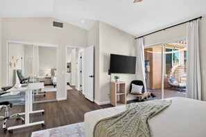 Ein modernes Hotelzimmer mit Bett, Schreibtisch, Stuhl, Fernseher und Blick ins Freie.