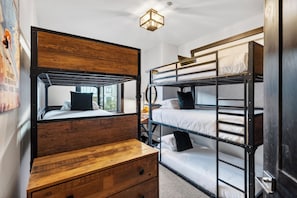 A bunk bed room with a wooden headboard, a nightstand, and a wall-mounted light fixture. - Private Hot Tub + BBQ + Communal Pool | Walk to Lifts | Blackstone Chalet (Park City)