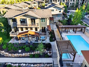 A multi-story building with balconies, a swimming pool, and outdoor seating areas. - Private Hot Tub + BBQ + Communal Pool | Walk to Lifts | Blackstone Chalet (Park City)
