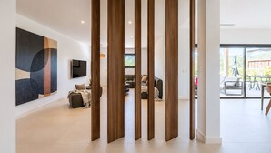 A modern interior with a sectional sofa, a flat-screen TV, and a large abstract painting. - Villa Déoni (Zonza)