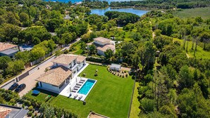 An aerial view of a residential area with a swimming pool, houses, and a lake. - Villa Déoni (Zonza)