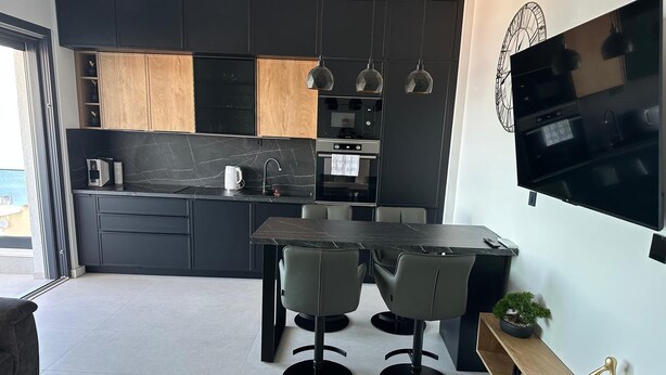 Uma cozinha moderna com área de refeições, eletrodomésticos embutidos e televisão de tela plana.