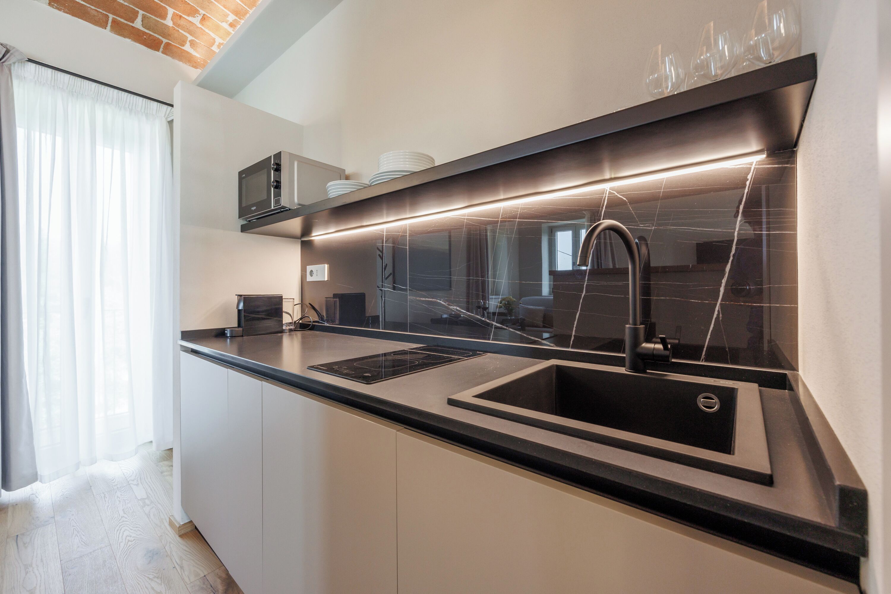 A modern kitchen with a black countertop, stainless steel appliances, and a large window.
