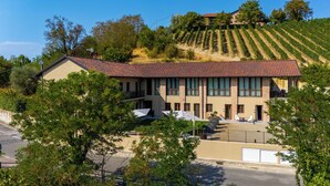 A two-story building with a red-tiled roof, large windows, and a balcony. - Calanga (Barbaresco)