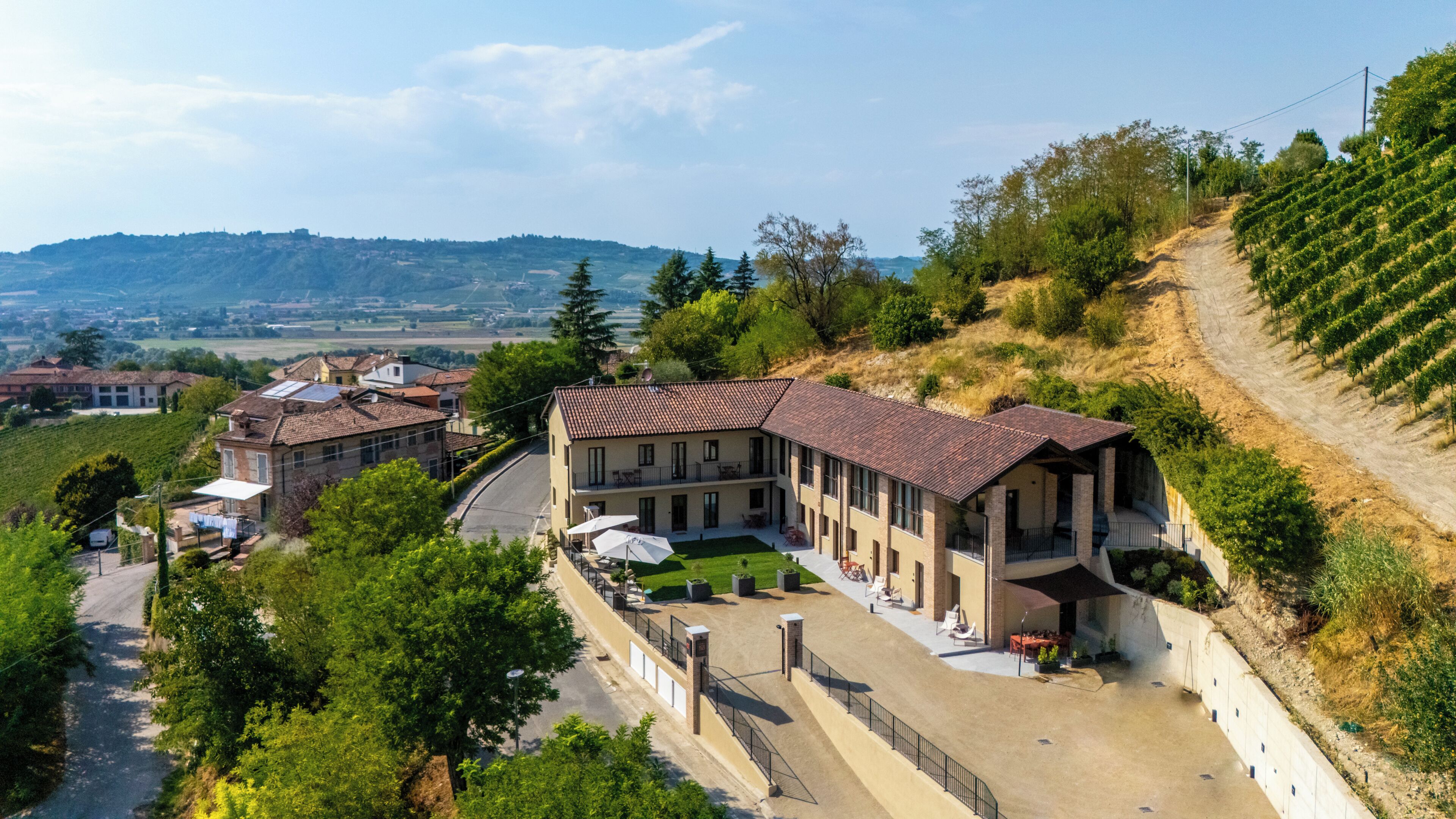 A villa with a courtyard, surrounded by vineyards, and a view of the countryside.