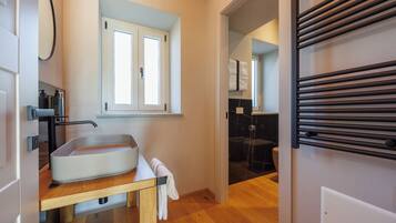 Une salle de bain équipée d’un lavabo, d’un miroir, d’un porte-serviettes et d’une fenêtre.