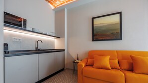 A compact living space with a kitchenette, a sofa, and a painting on the wall. - Calanga (Barbaresco)