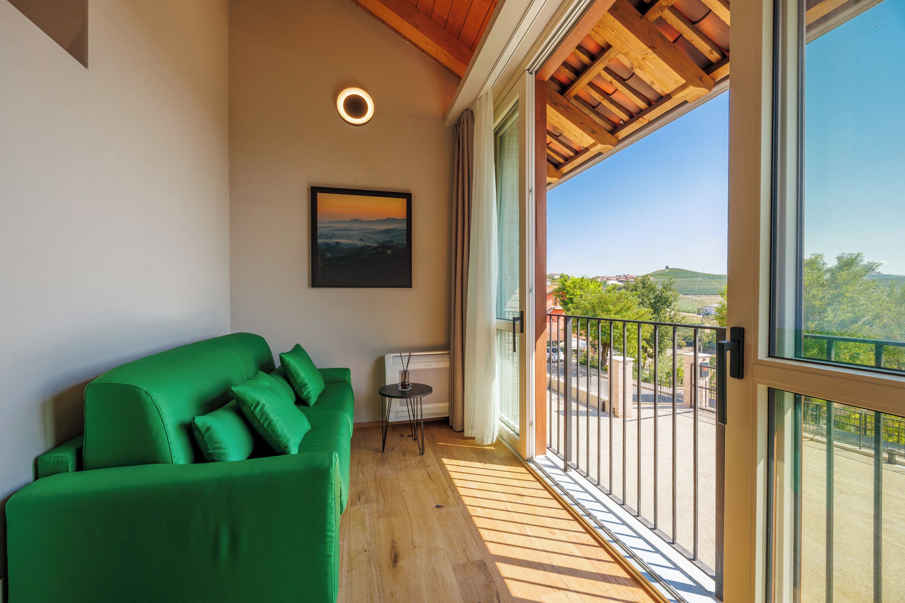 A balcony with a green sofa, a small table, and a painting on the wall.