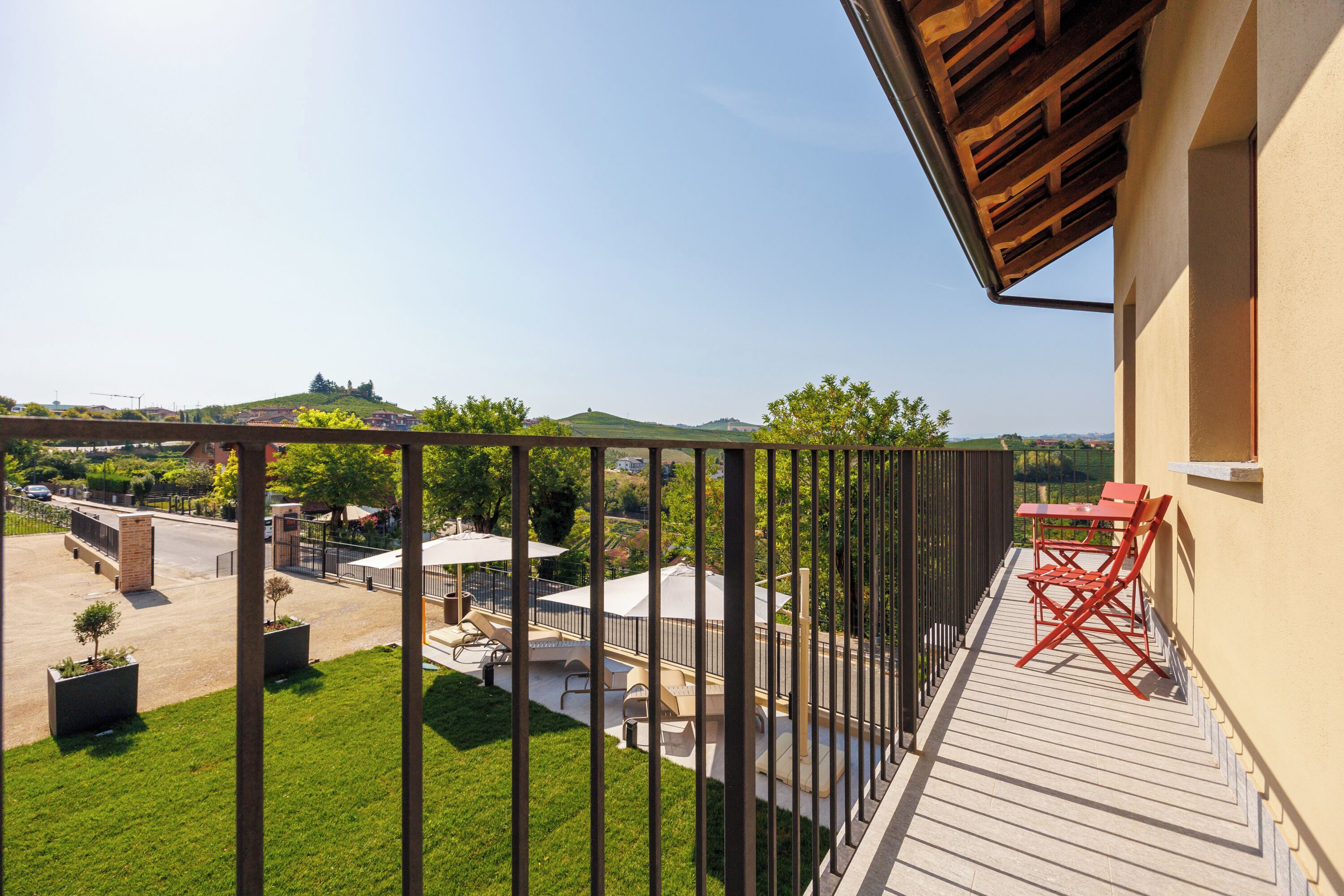 A balcony with a view of a green landscape and a distant hill.