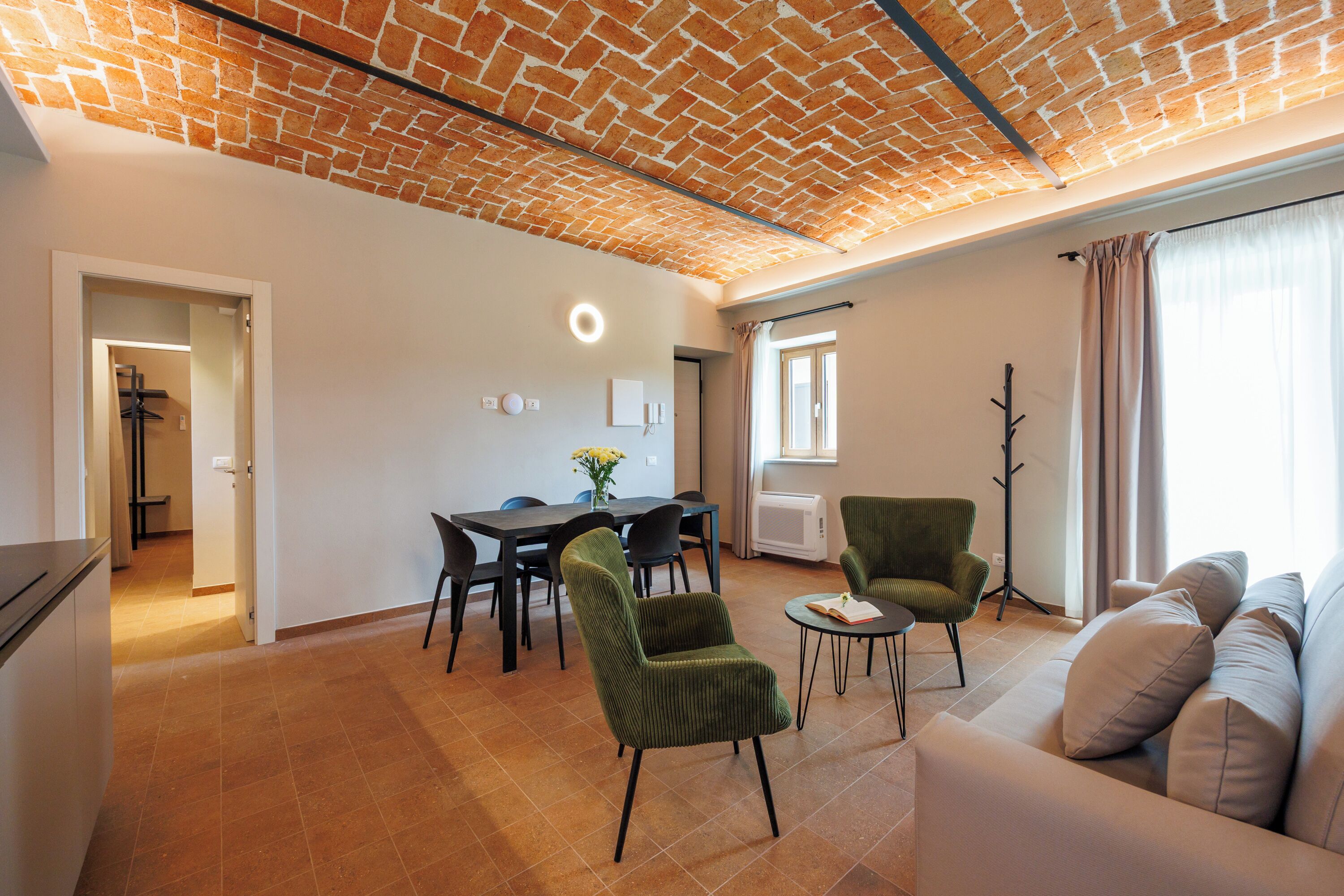 A modern living room with a brick ceiling, a dining area with a table and chairs, and a seating area with a sofa and armchairs.