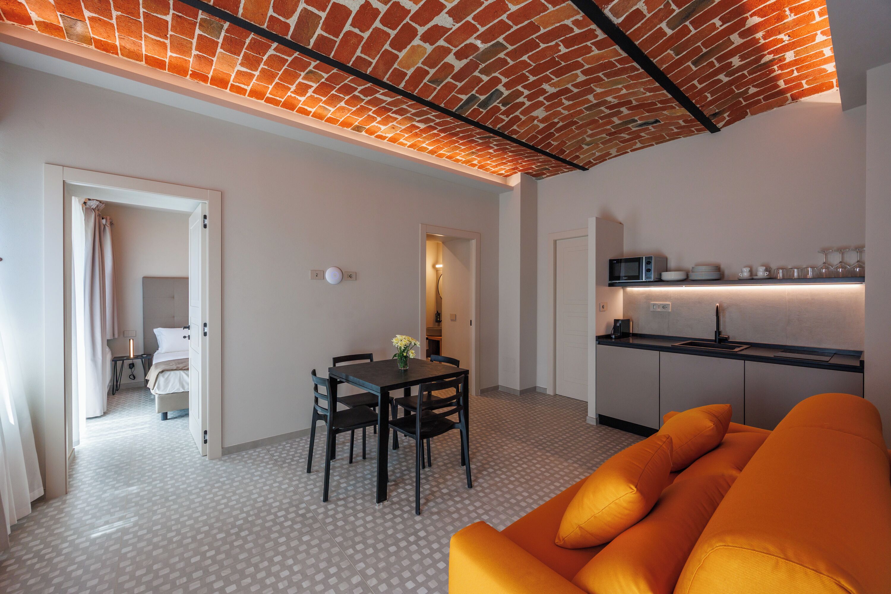 A modern interior with a dining area, kitchen, and a bright orange sofa.