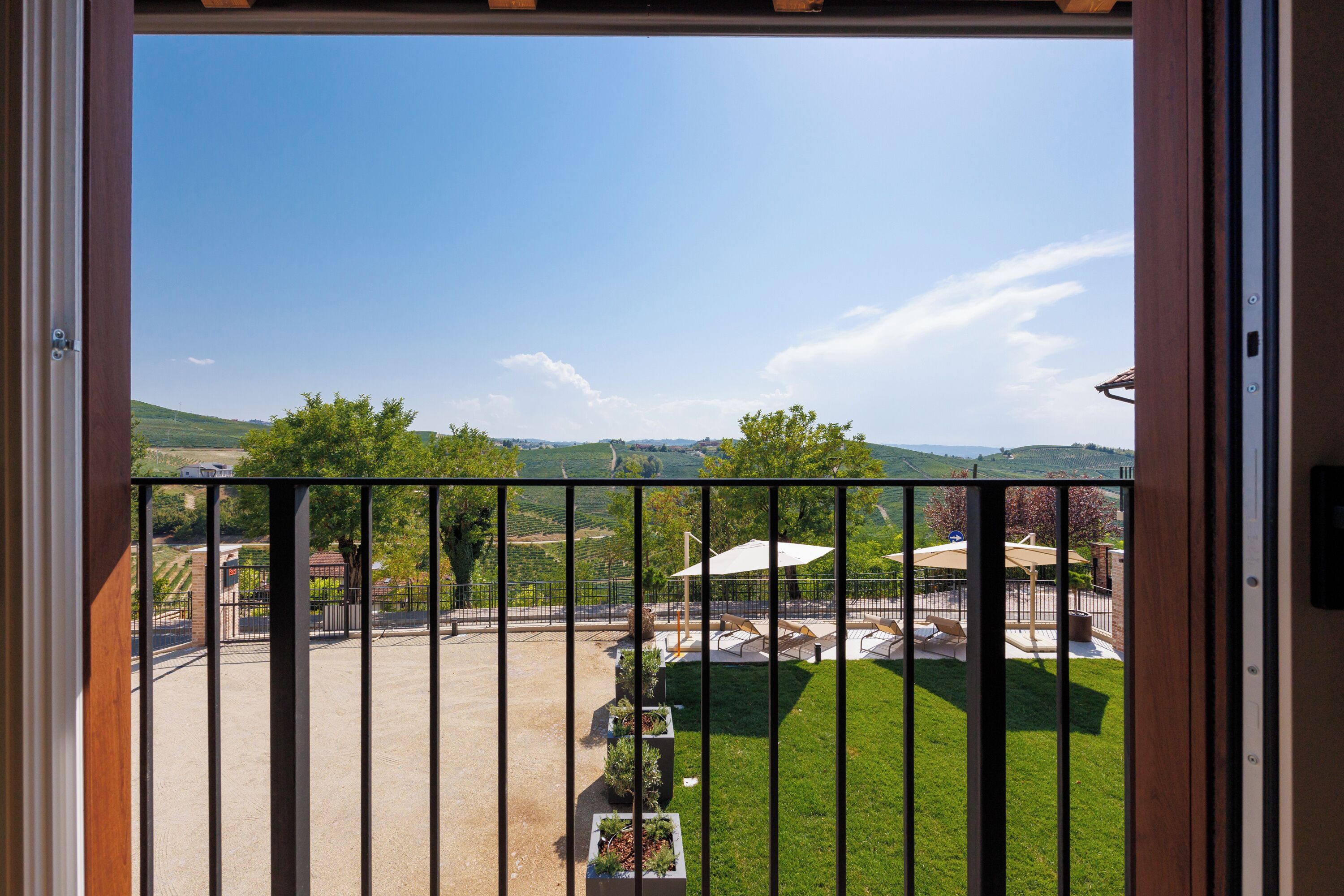Een balkon met uitzicht op een wijngaard en heuvels in de verte.