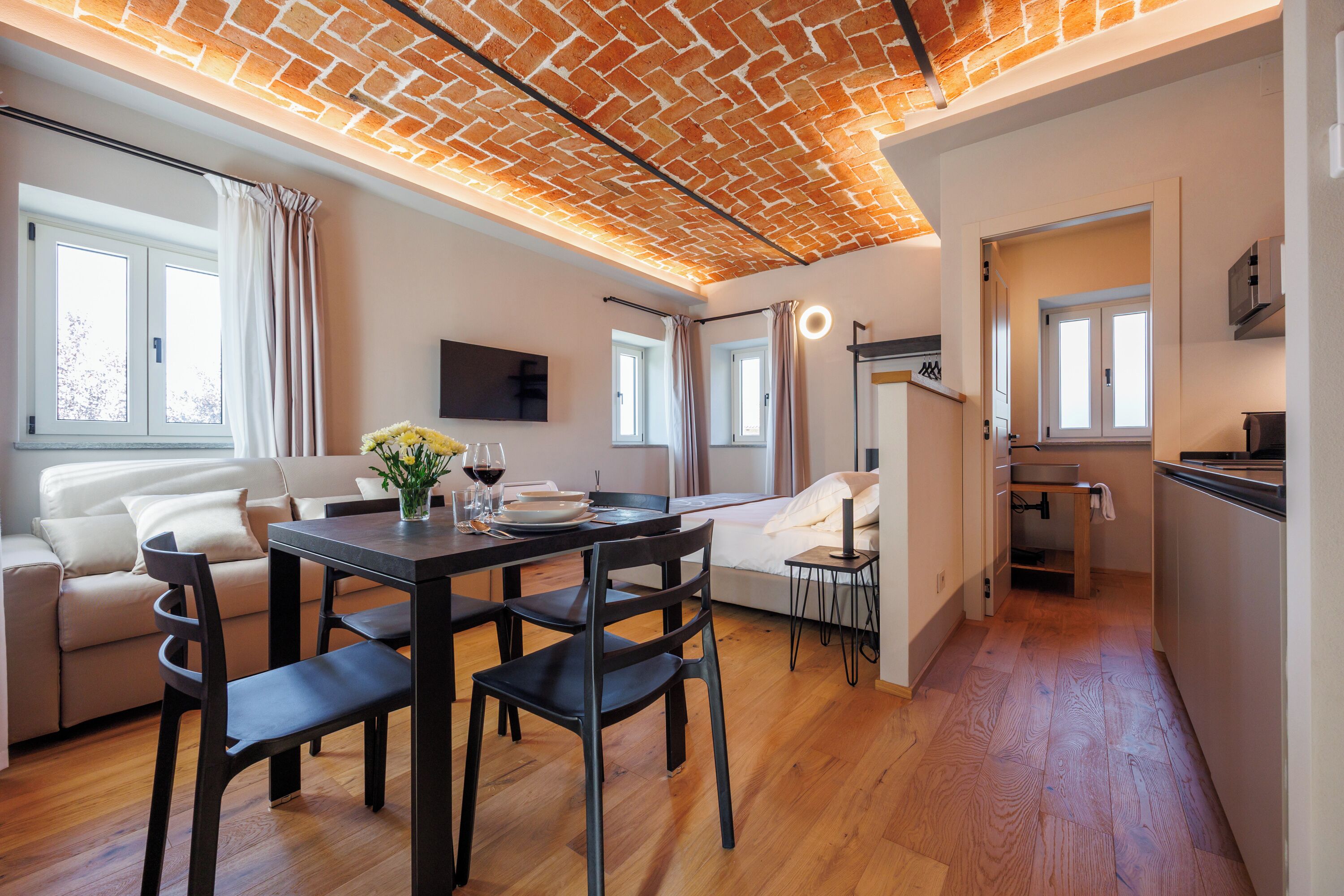 Un soggiorno moderno con zona pranzo, divano, televisore e angolo cottura.