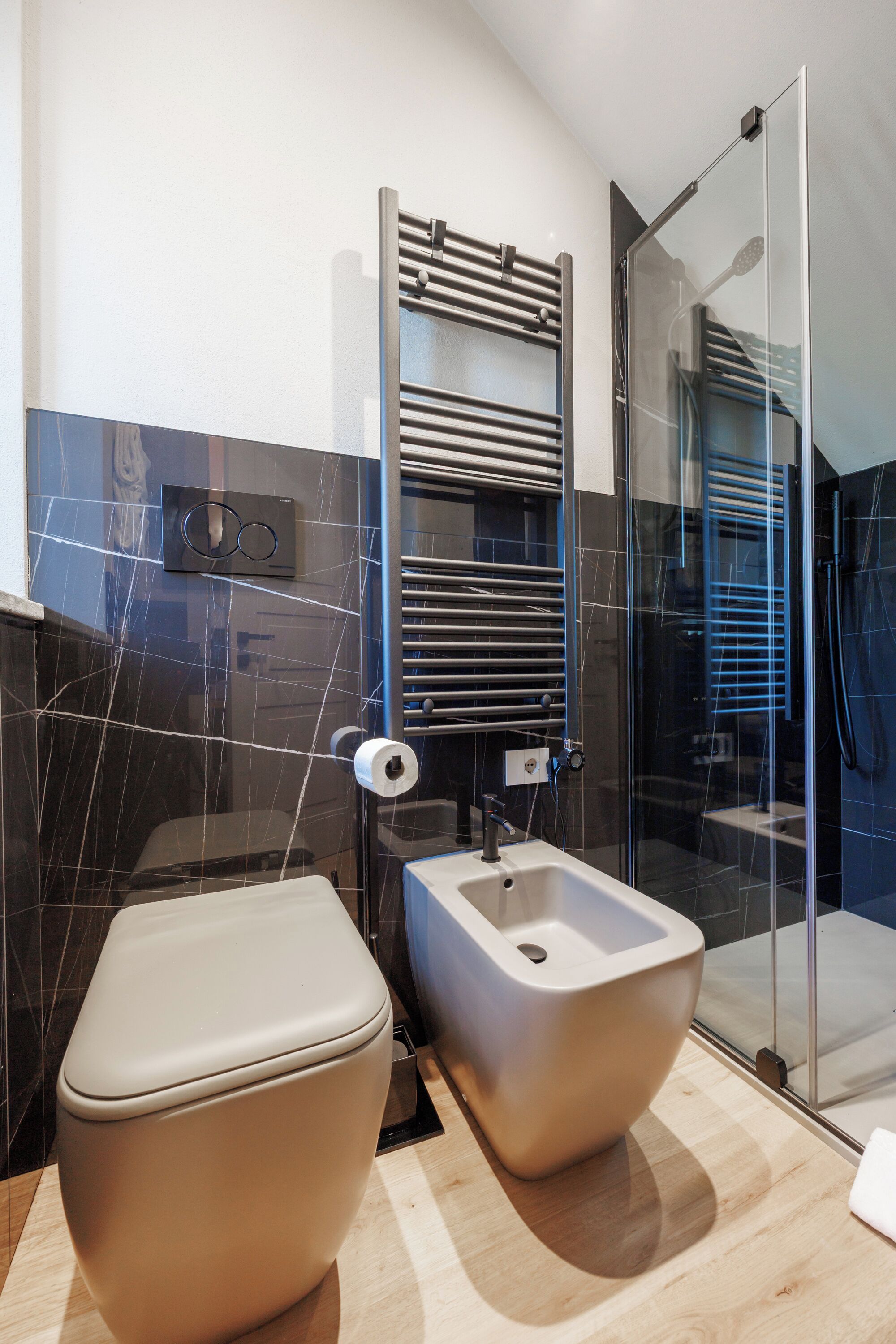 Un baño moderno con inodoro, bidé y cabina de ducha de vidrio.