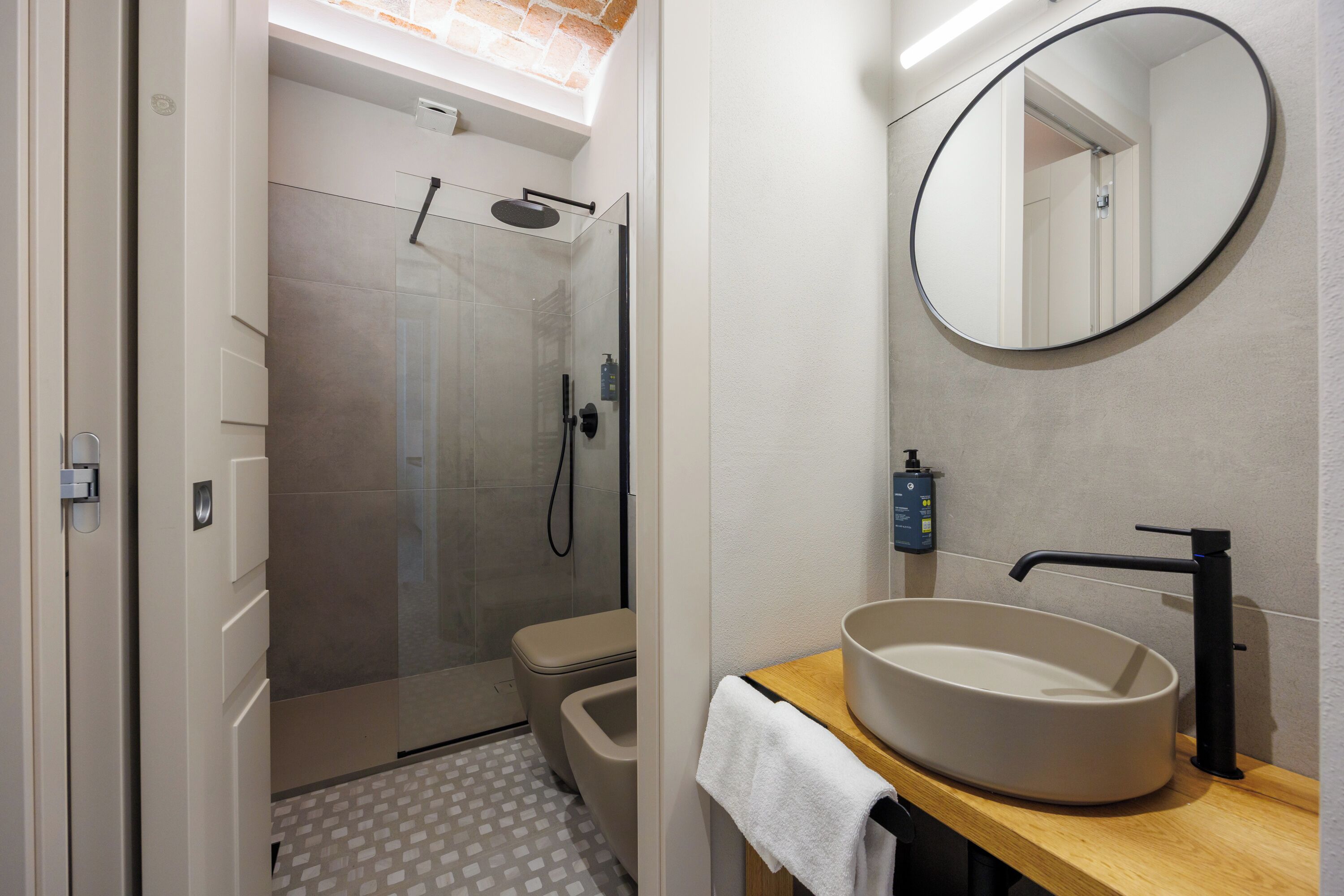 Un baño moderno con ducha de vidrio, inodoro y lavamanos de diseño circular.