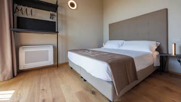 Un dormitorio con una cama, un calentador, un estante con perchas y una lámpara en el techo.