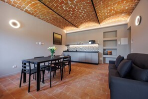 Una cocina moderna con techo de ladrillo, un área de comedor con mesa y sillas, y un sofá.
