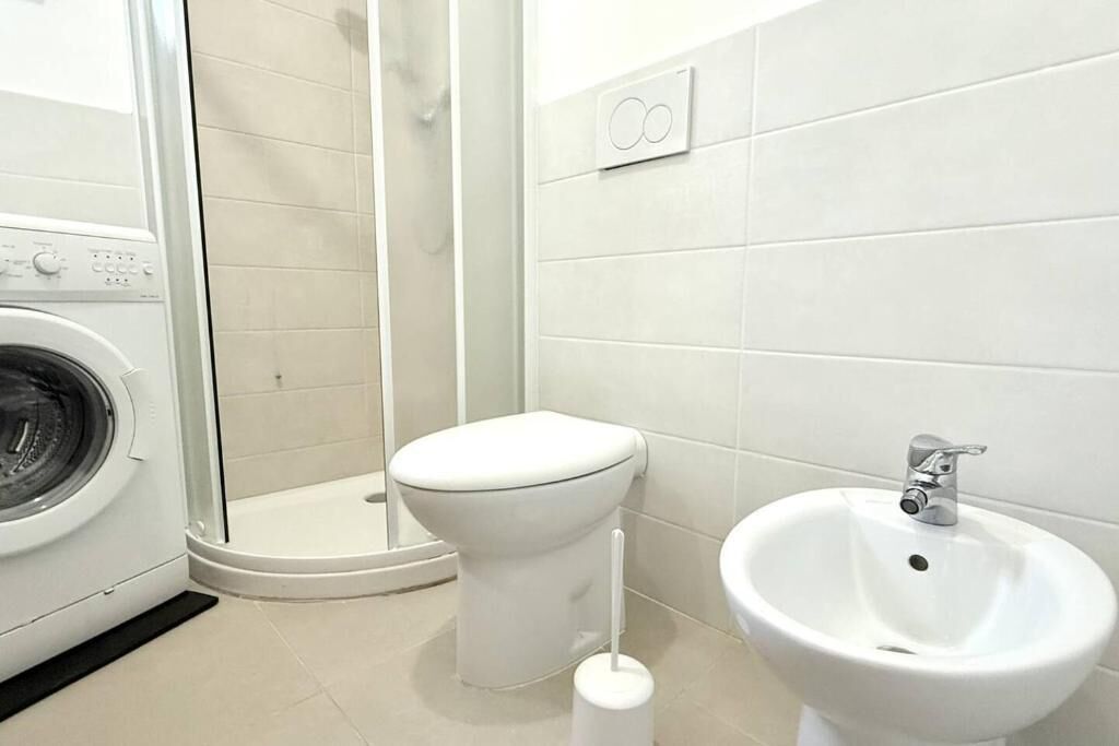 A bathroom with a washing machine, toilet, and sink.