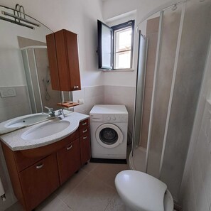 Ein kleines Badezimmer mit einem Waschbecken, einer Waschmaschine und einer Toilette.