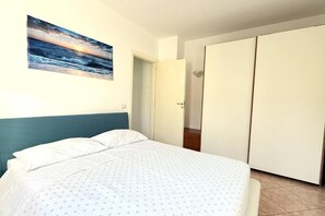 A bedroom with a bed, a painting, and a wardrobe. - Casa Zefiro – Private entrance with a courtyard, 10 minutes from the beach (Marzocca)