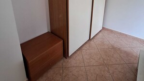 Een kamer met een houten bank, een witte kast en een betegelde vloer.