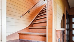 A wooden staircase with a handrail, leading to a door with a window.