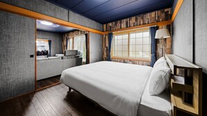 A bedroom with a bed, a seating area, and a window with curtains.