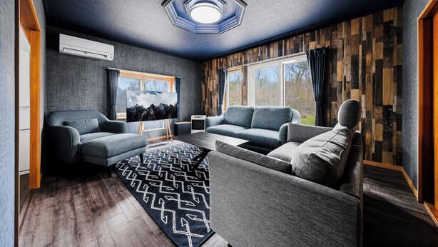 A modern living room with a sectional sofa, a patterned rug, and a large window with curtains.