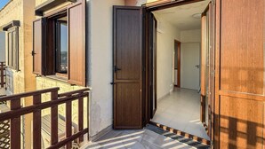Ein Wohngebäude mit einer Holztür, einem Balkon mit Geländer und einem Fliesenboden.