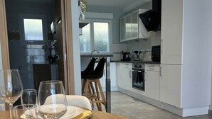 Un'area pranzo con un tavolo apparecchiato per due, una cucina sullo sfondo e vista all'esterno.