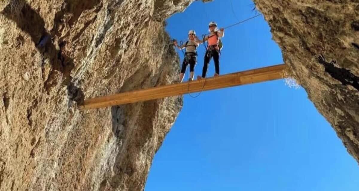 Une poutre en bois suspendue entre des formations rocheuses.