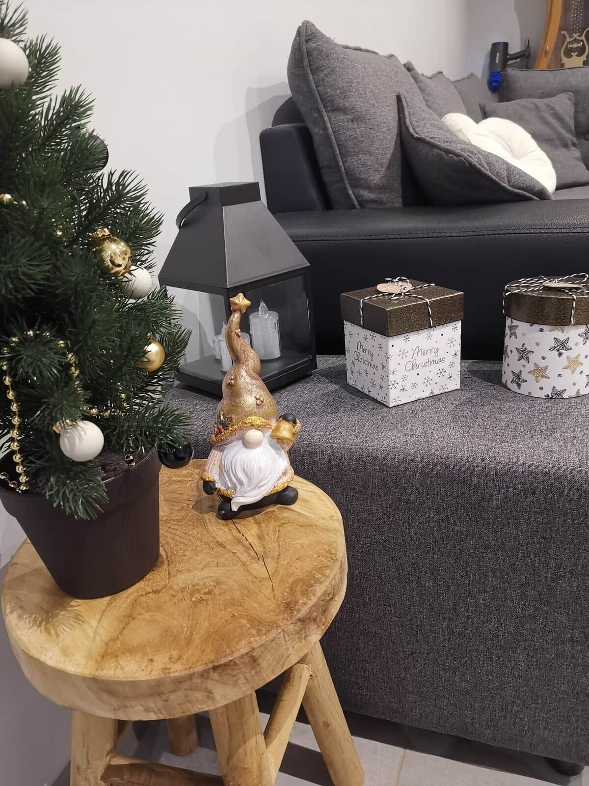 Una pequeña mesa de madera con un árbol de Navidad, una figurita de gnomo y dos cajas de regalo.