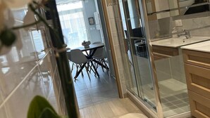 Una cucina moderna con una porta vetrata che dà su un'area pranzo, una pianta in vaso e vista sulla sala da pranzo.