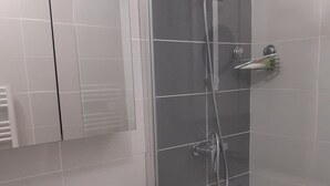 Et moderne badeværelse med en hvid vask, en glas brusekabine og et spejl over vasken.