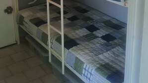 En køjeseng med tre niveauer, en dør og et flisegulv.