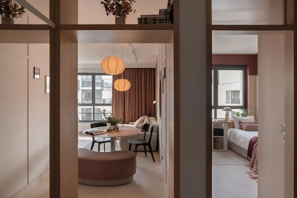 A modern interior with a dining area, a round seating area, and a bedroom with a window. - POPI Apartment 6, 2 Bedrooms Gdańsk Centre. Family & Pet-Friendly! (Gdańsk)