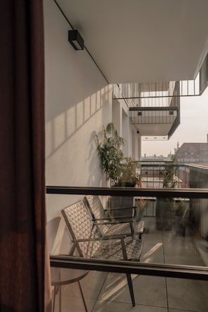 A balcony with a seating area, a potted plant, and a view of the cityscape. - POPI Apartment 6, 2 Bedrooms Gdańsk Centre. Family & Pet-Friendly! (Gdańsk)